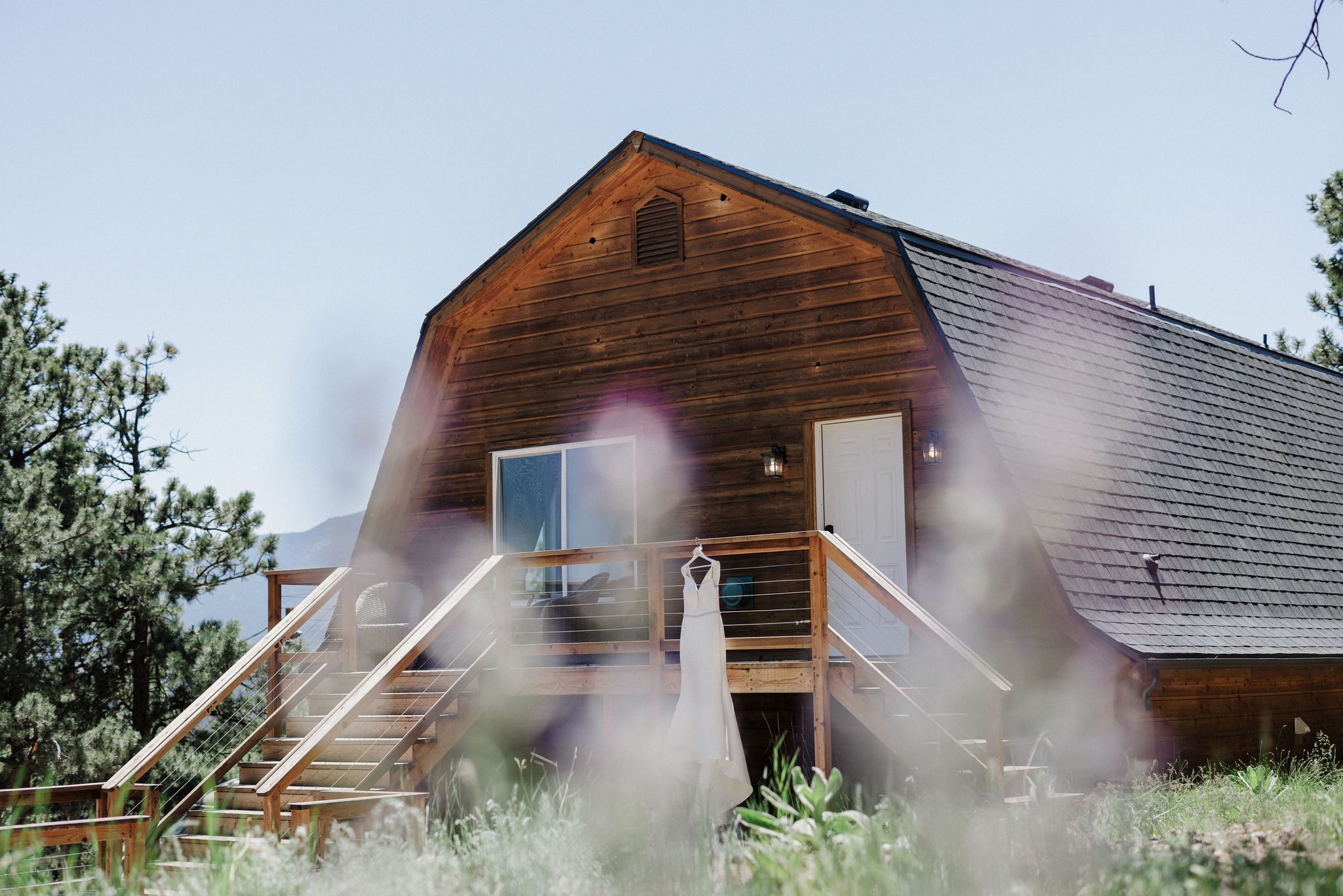 wedding dress hangs on the deck of a rustic airbnb in colorado