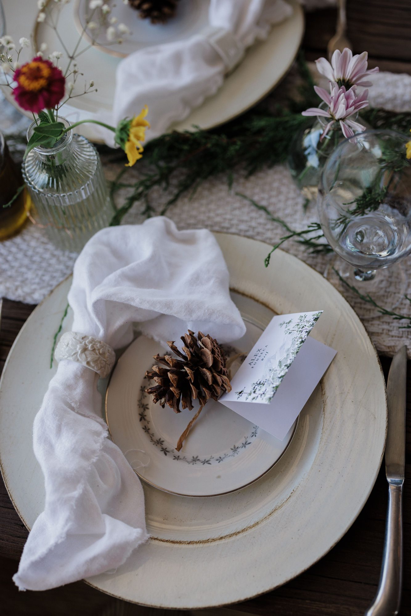 a dinner setup with a pinecone and wildflowers are set up for a micro wedding reception.