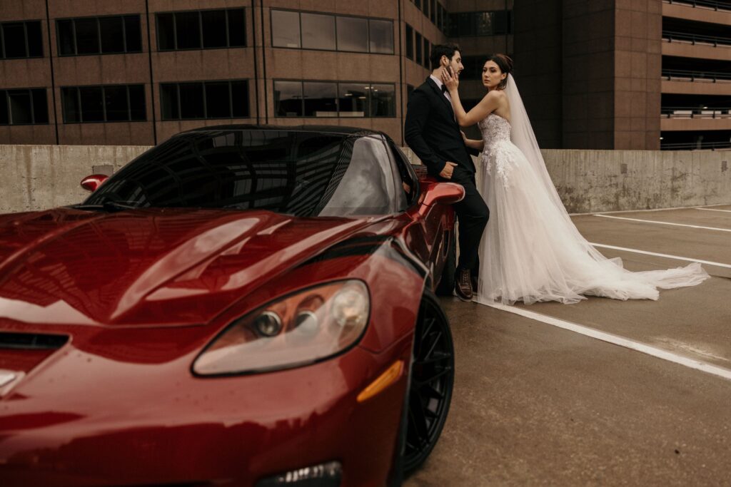 Bride and groom pose beside red car for elopement photographer during colorado bridal portraits.