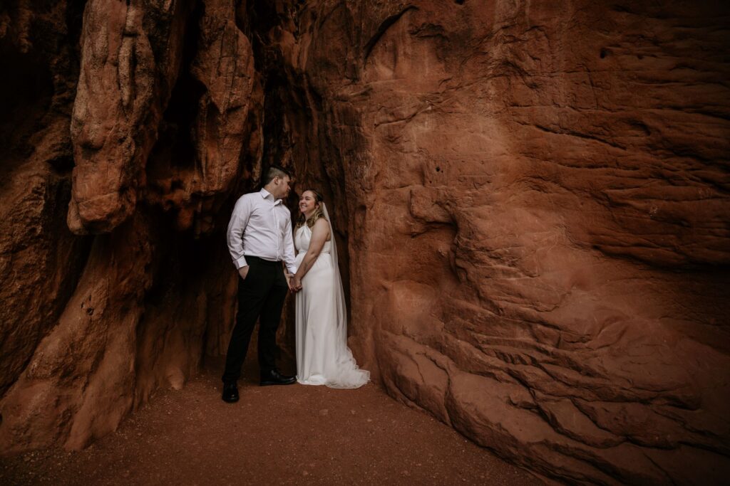 bride and groom stand in between rocks during wedding portraits in garden of the gods.