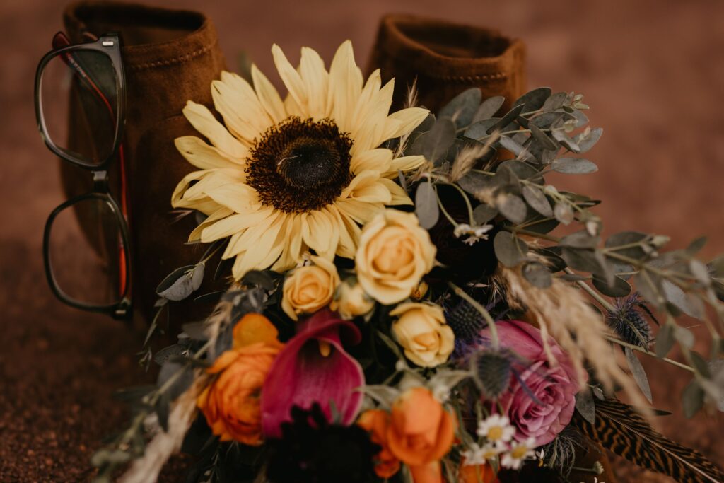 elopement details during colorado wedding photos- wedding bouquet, boots, glasses
