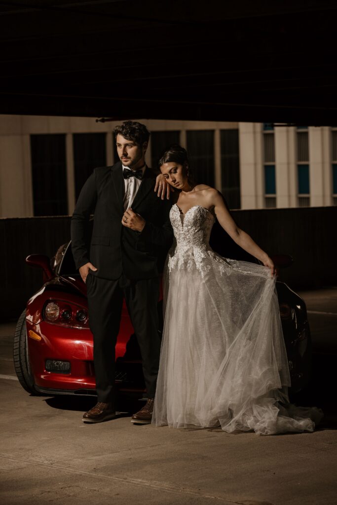 couple poses in front of red sportscar during downtown denver bridal portrait photos.