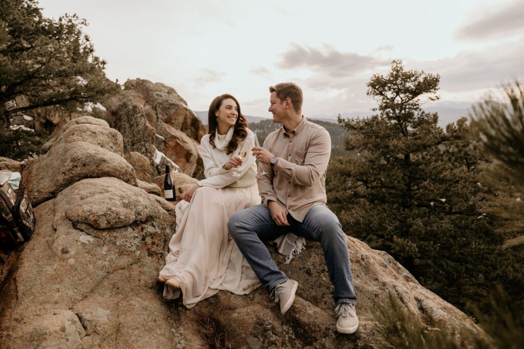 bride and groom cheers sitting on a rock during colorado mountain elopement.