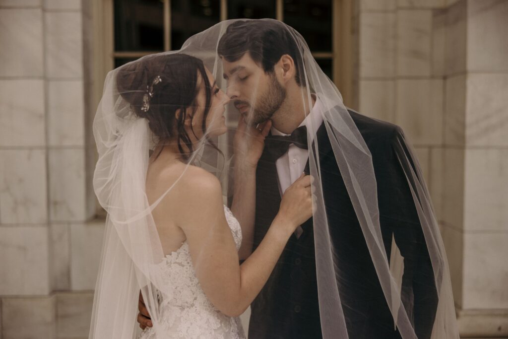 bride and groom kiss under veil during colorado bridal portraits in downtown denver.
