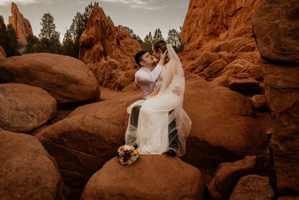 newlywed couple sits on red rocks during colorado adventure elopement.