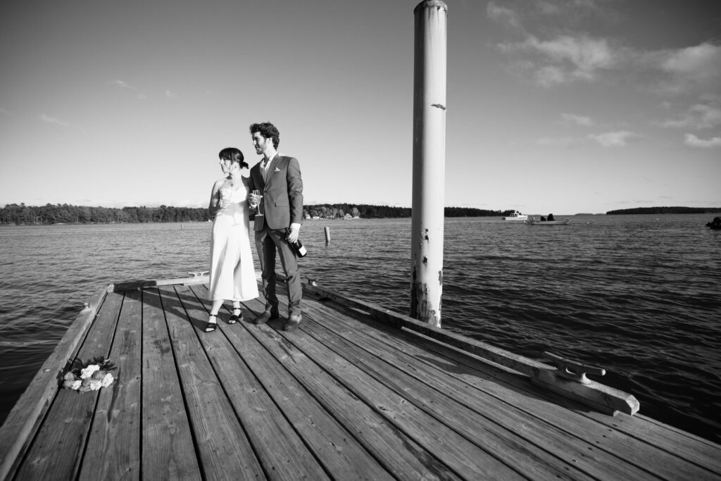 bride and groom stand on dock during lake adventure elopement in colorado.