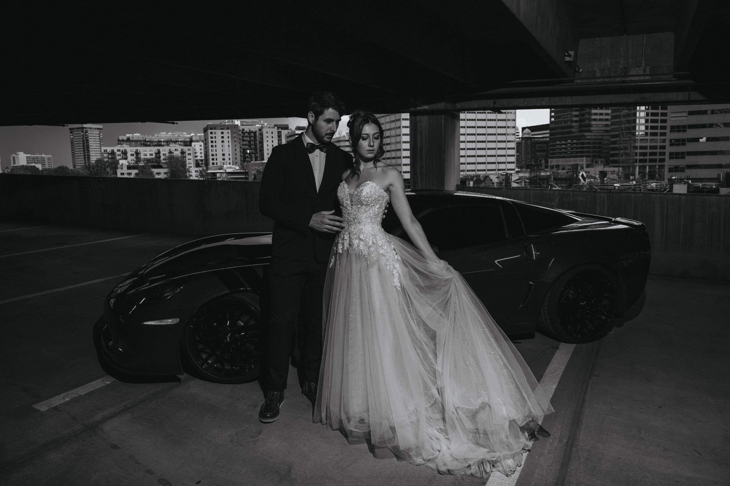 bride and groom pose for denver elopement photographer beside car during bridal portraits