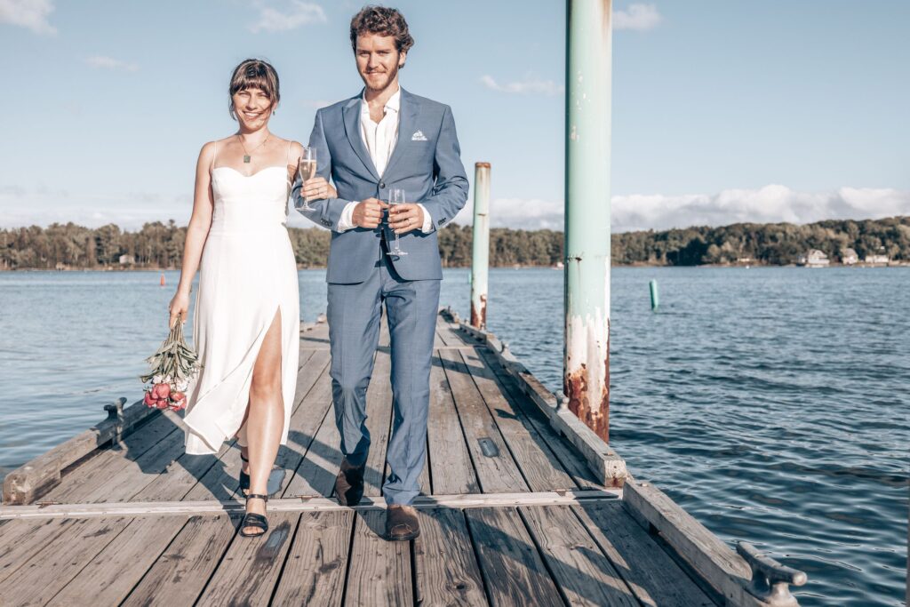 bride and groom walk down dock during wedding portraits at point park in colorado.