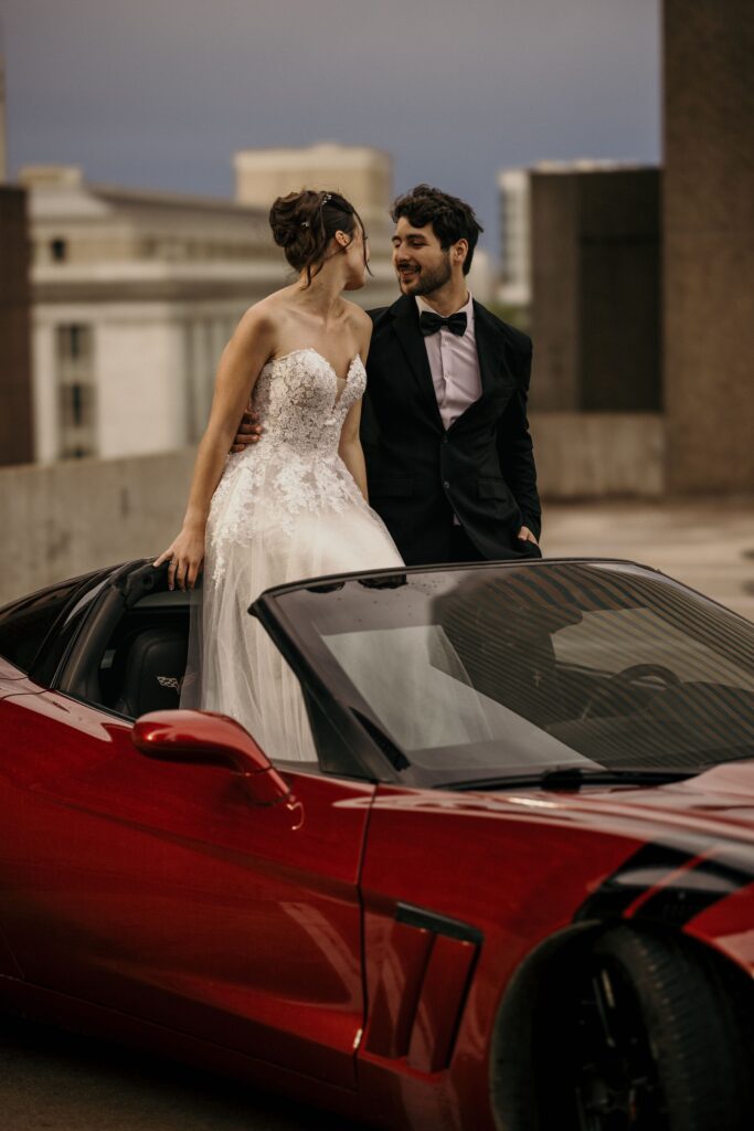 groom and bride sit inside of sportscar during urban bridal portrait photos.