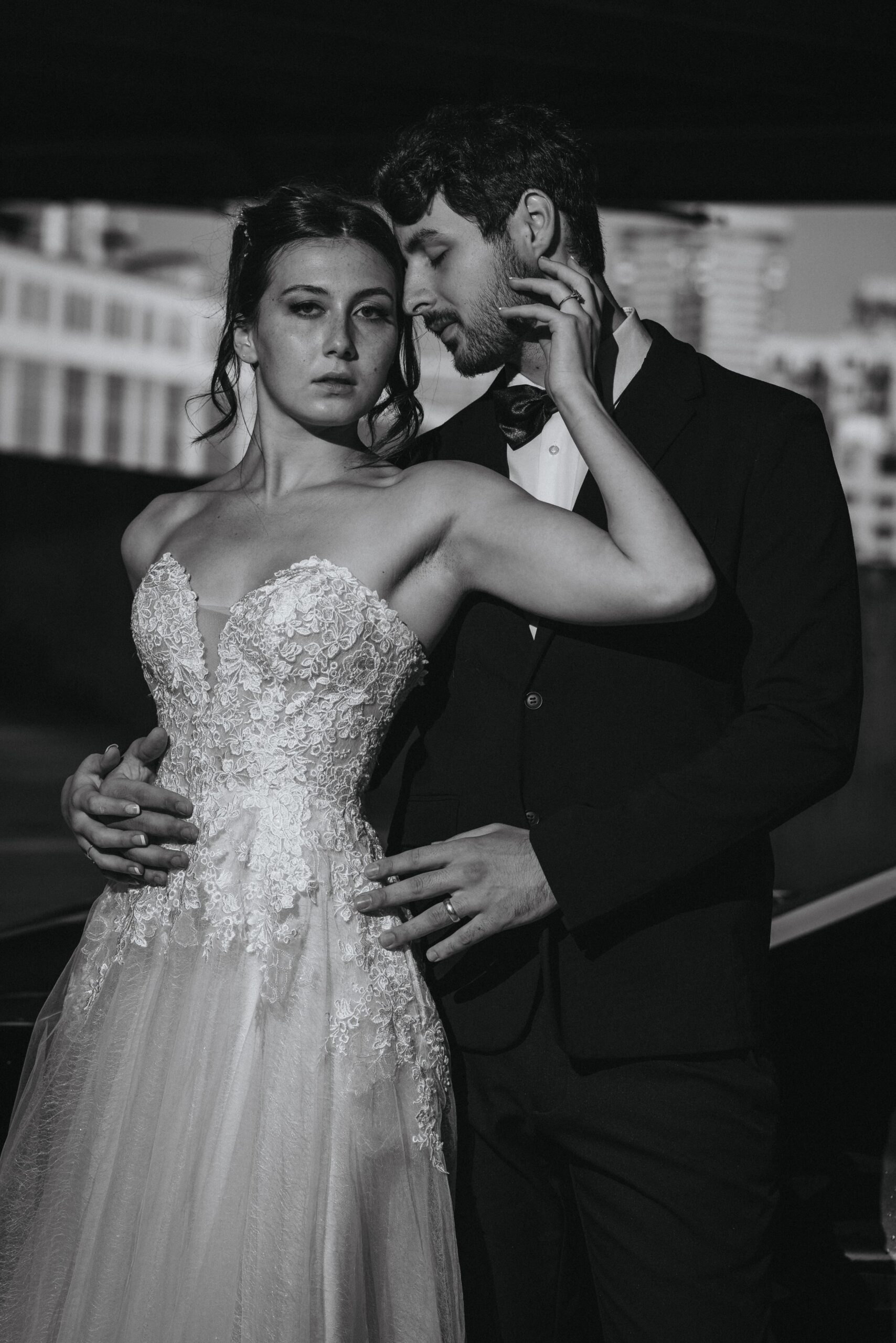 black and white image of groom standing behind bride leaning his forehead against hers, during bridal portraits.