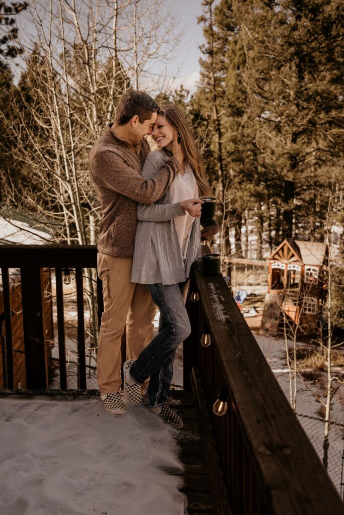 Couple standing on a snowy deck during couples portraits by Colorado elopement photographer.