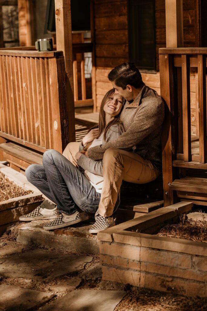 A couple sits on the porch of an Airbnb while getting engagement photos done by colorado wedding photographer.