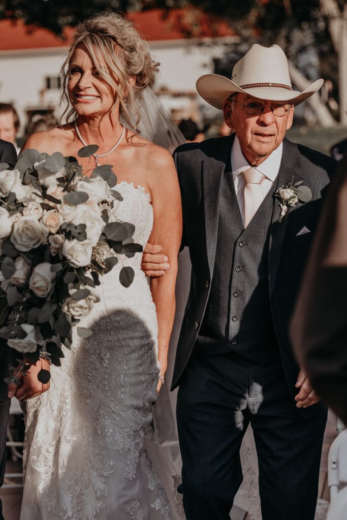 bride and father walk down the aisle during rustic wedding in colorado.