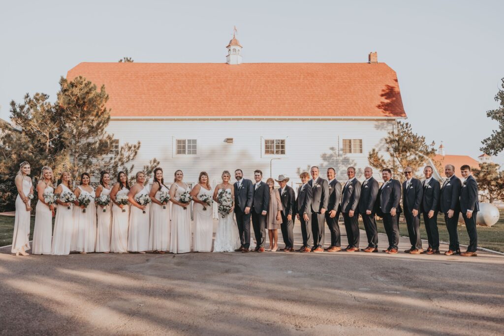 wedding party stands in front of barn during western wedding portraits.