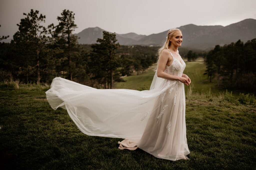 bride stands with dress in the wind, during photos with colorado wedding photographer.
