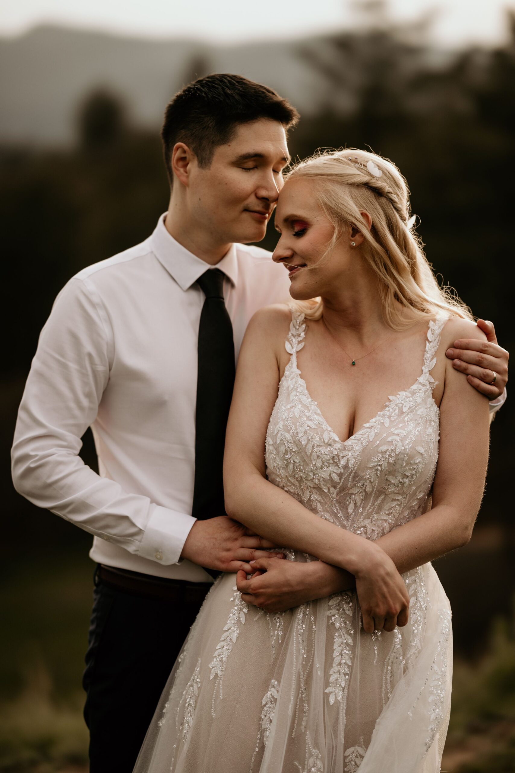 bride holds onto grooms arms and leans her head on his shoulder during wedding portraits in colorado springs.