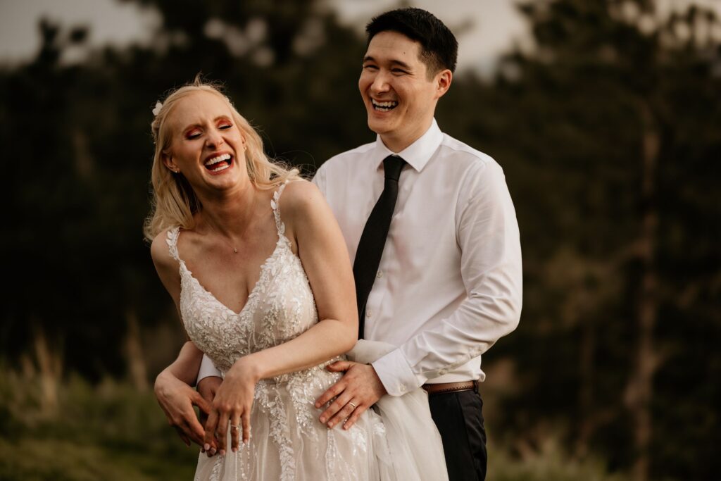 newlywed couple embraces each other and laughs during wedding portraits in colorado springs.