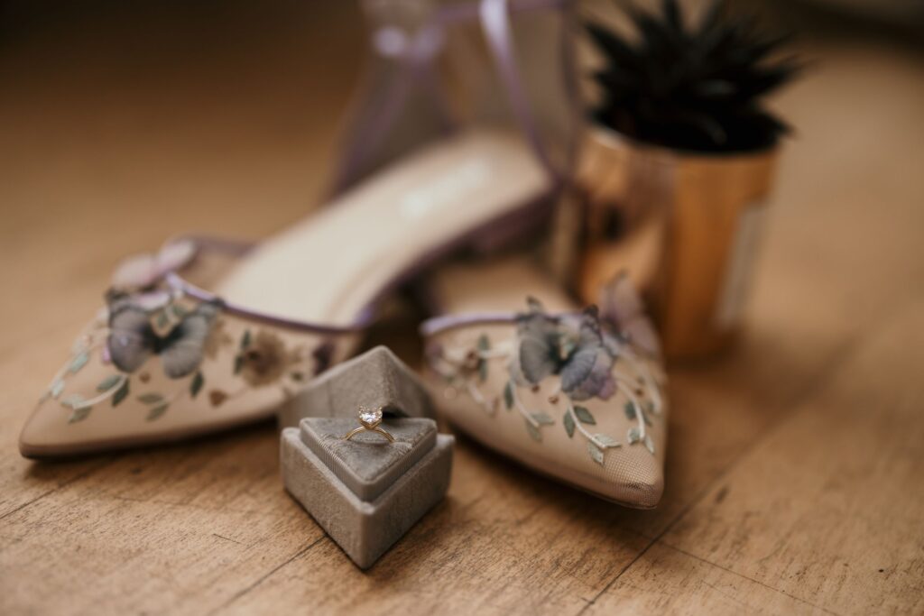 close up image displaying wedding details, wedding ring and purple and cream shoes.