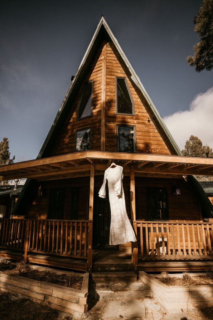dress hangs on porch of airbnb cabin during wedding photos with colorado elopement photographer.
