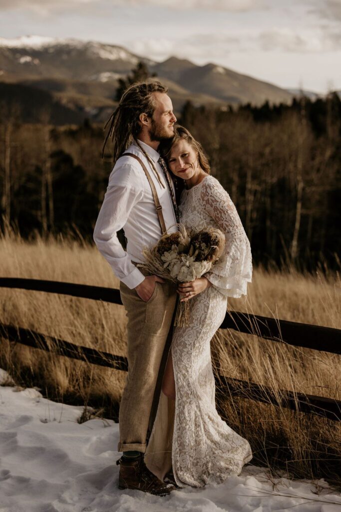 bride and groom embrace, with mountains in the background, during rustic colorado wedding.