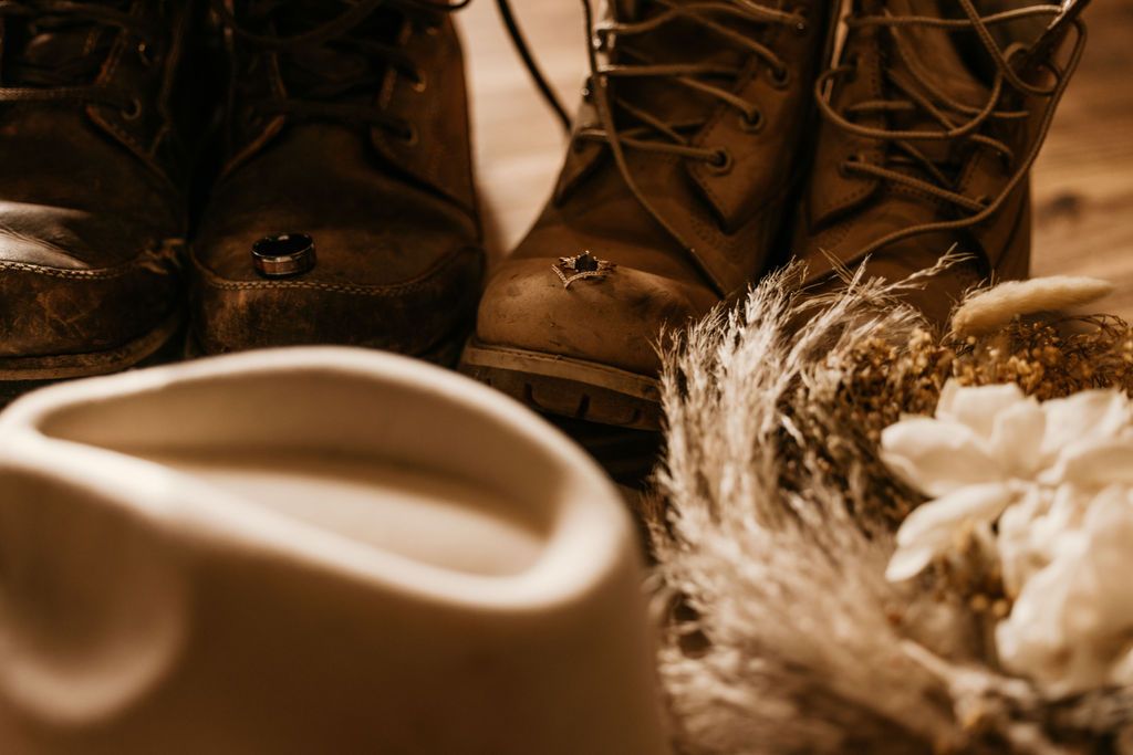 photo of western wedding details: boots, a western hat, and a dried flower bouquet.