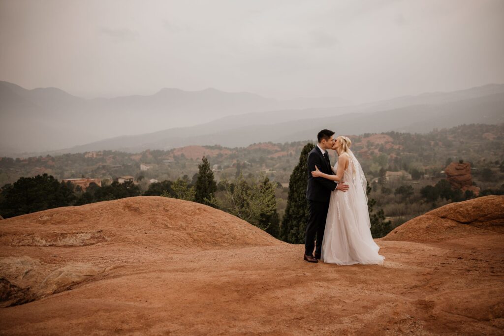 bride and groom stand on red rock at garden of the gods elopement photo session.