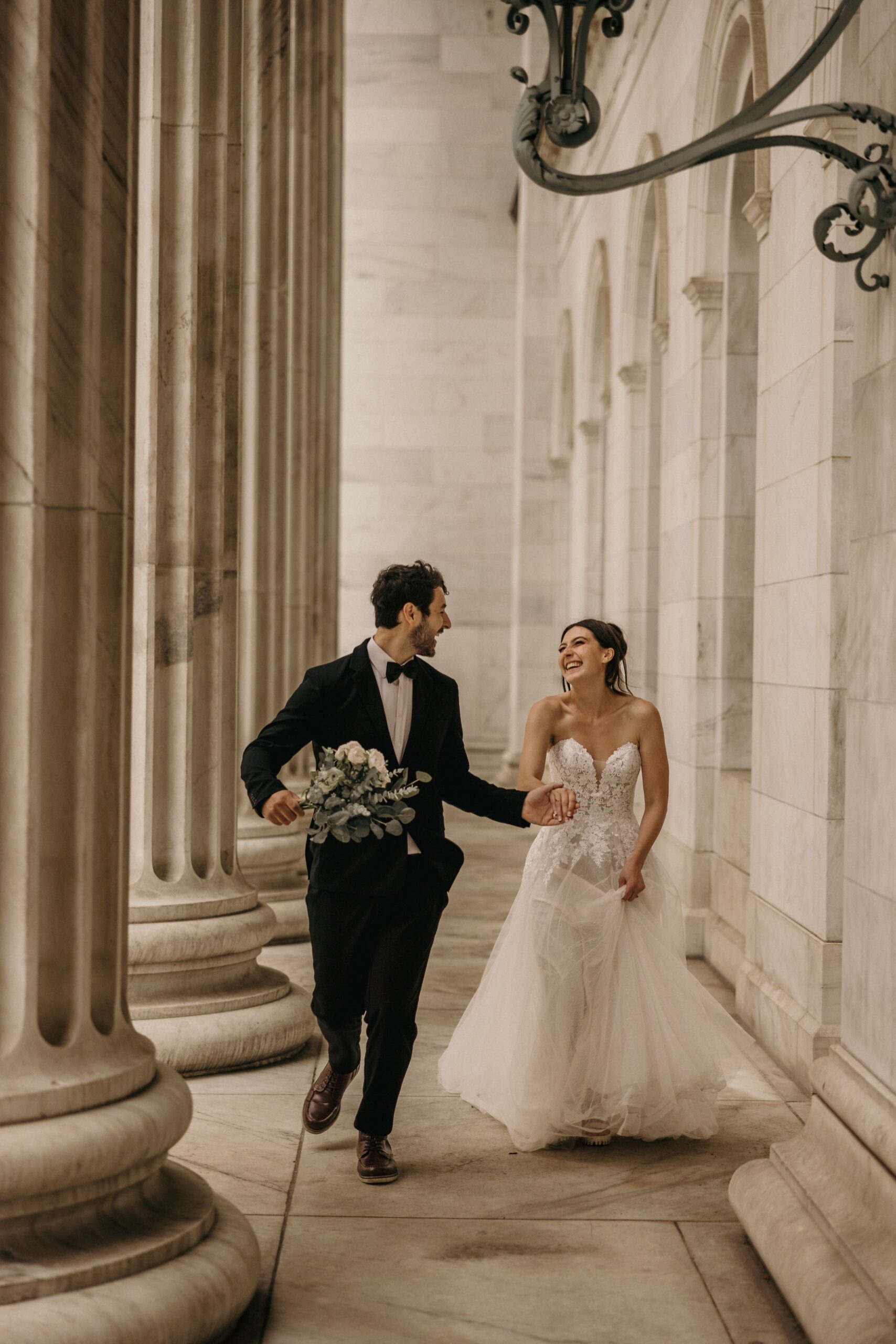 groom and bride run through marble columns during byron white courthouse elopement in colorado.