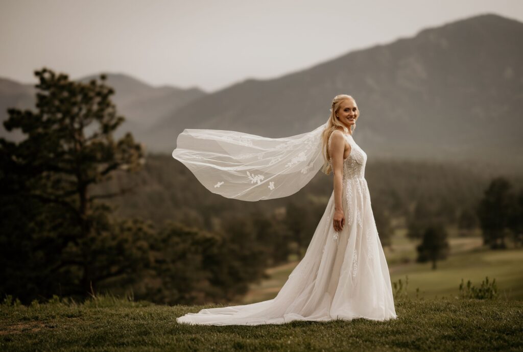 bride stands with veil in the wind, during photos with colorado wedding photographer.