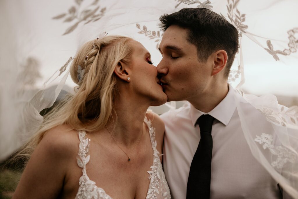 newlywed couple kisses under veil during colorado wedding photo session.