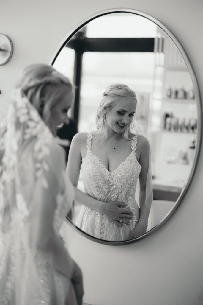 black and white image of bride's reflection in mirror during pre wedding party photos.