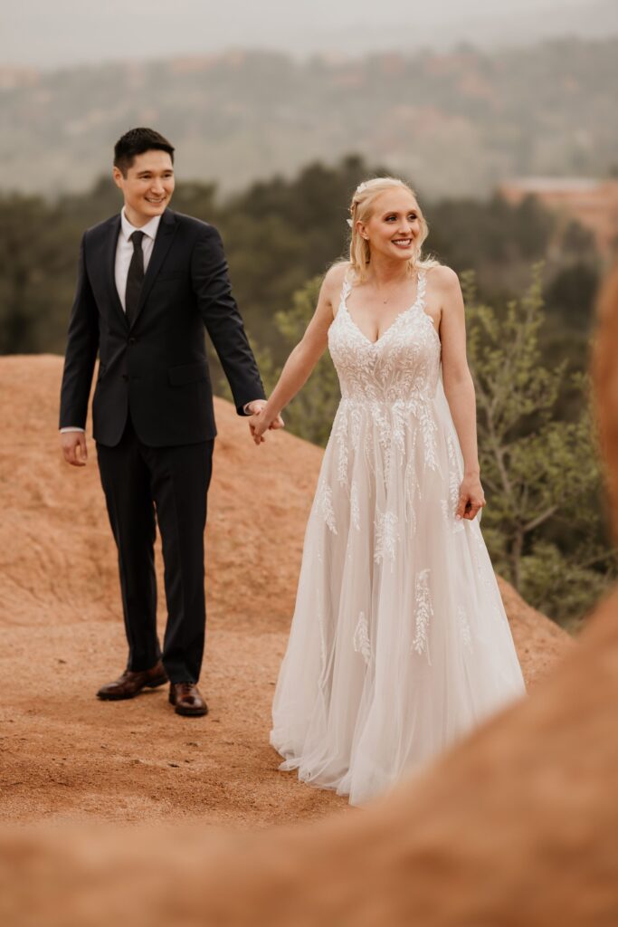 couple holds hands at garden of the gods in colorado springs during wedding photo session.