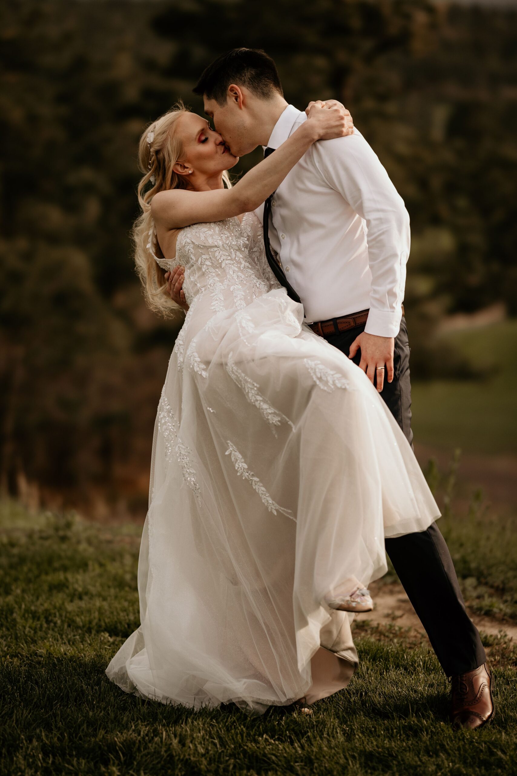 groom dips bride and kisses her during wedding portraits in colorado springs Air Force Academy.