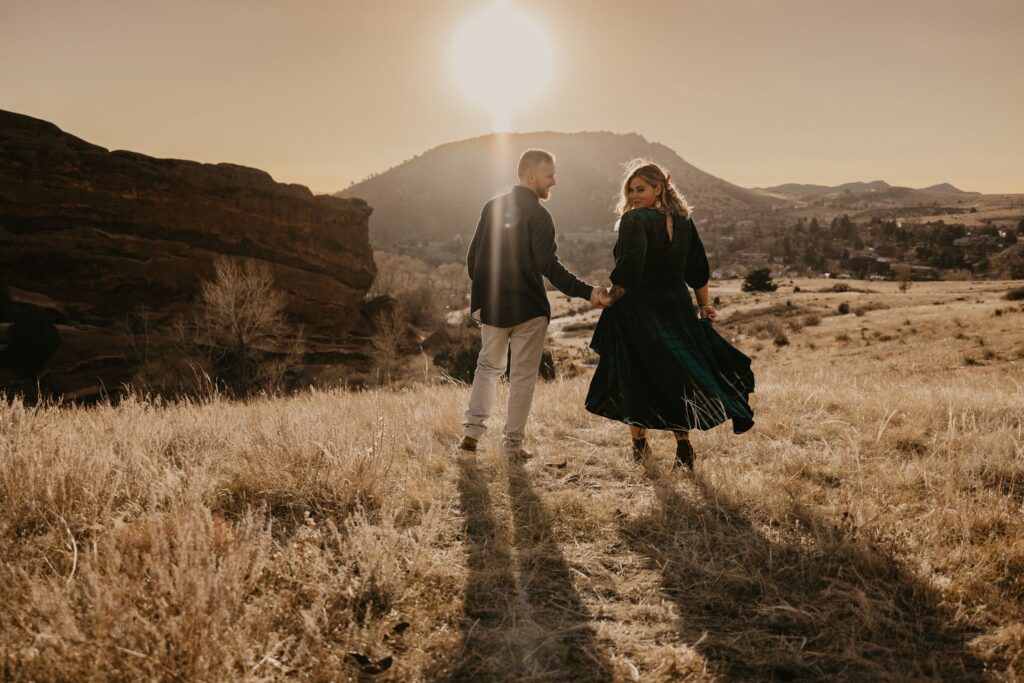 bride and groom walk down trail at red rocks park + amphitheater during colorado adventure elopement.