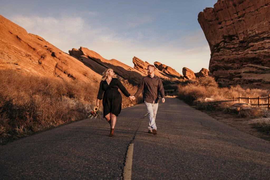 bride and groom walk down road during colorado adventure elopement at red rocks park + amphitheater.