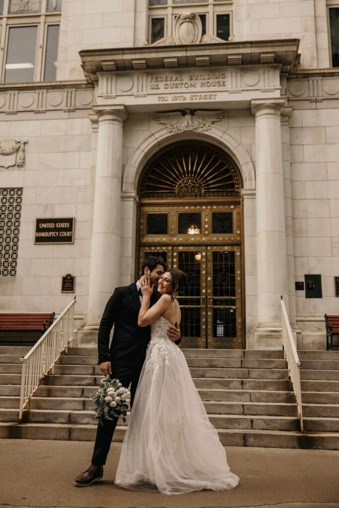 couple kisses in front of byron white courthouse for bridal portraits.