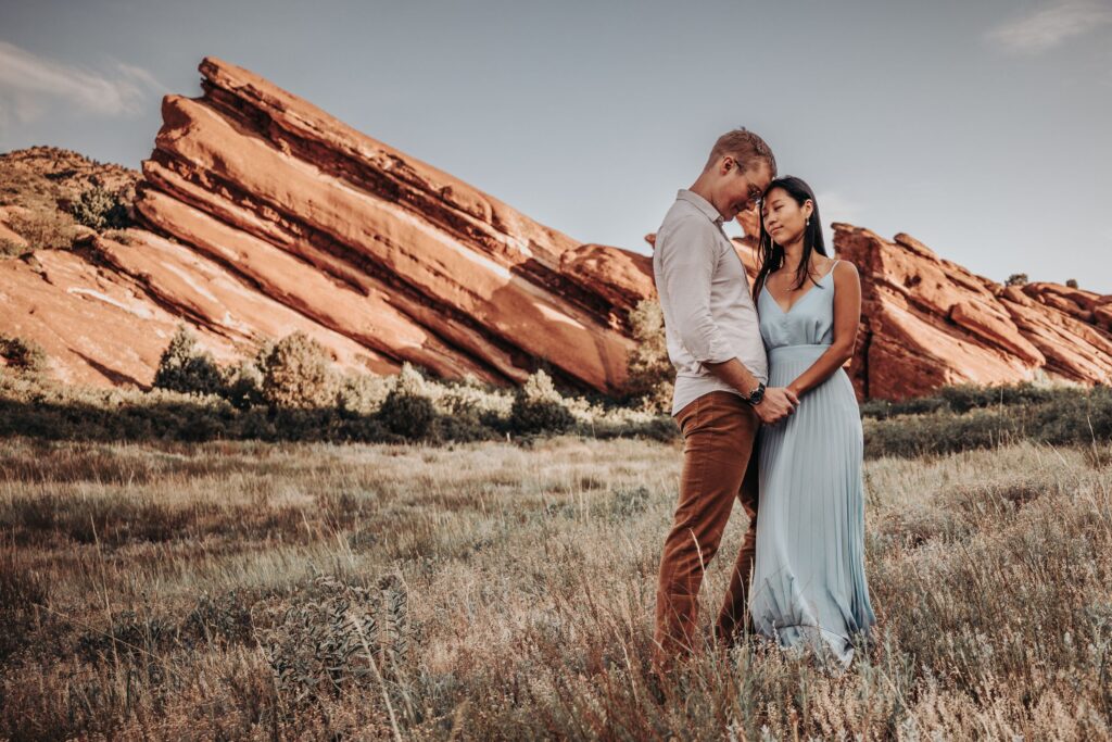 bride and groom walk down trail in red rocks park + amphitheater during colorado adventure elopement.