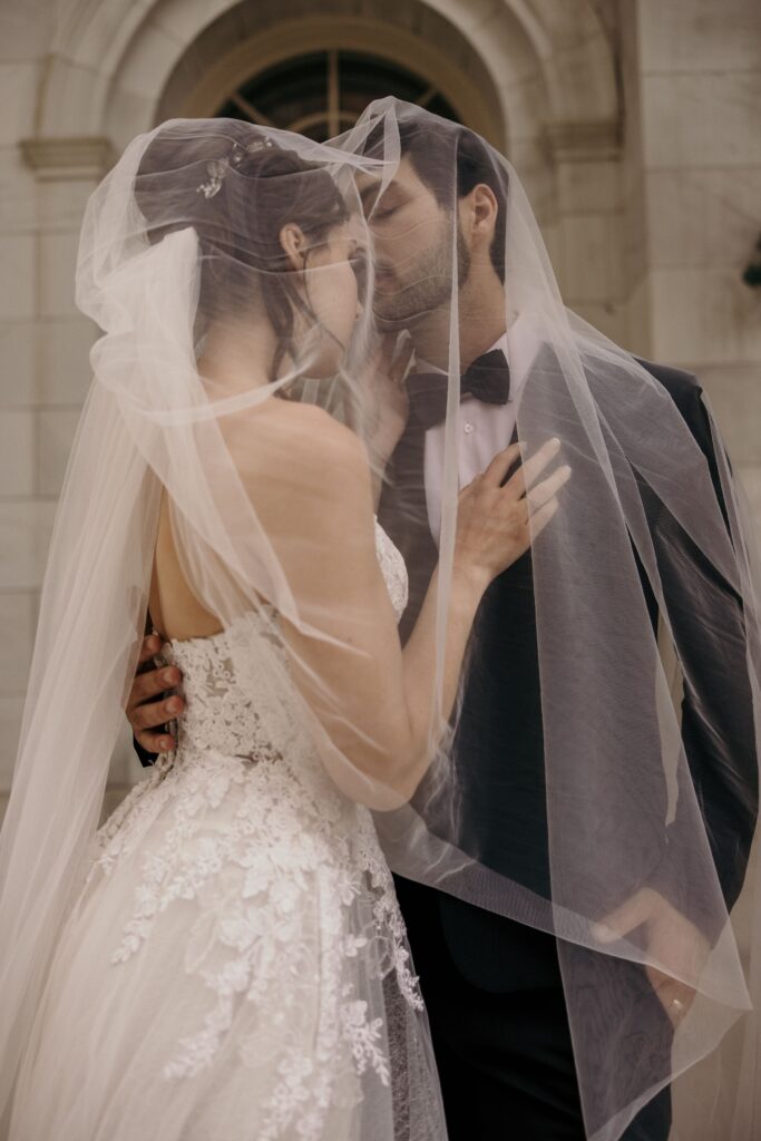 bride and groom kiss under her veil during downtown denver bridal portraits.