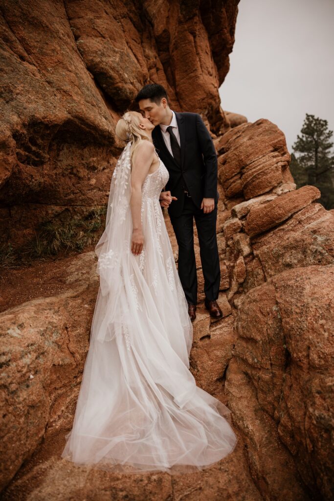 couple kisses on red rocks at colorado springs' garden of the gods during wedding photo session.