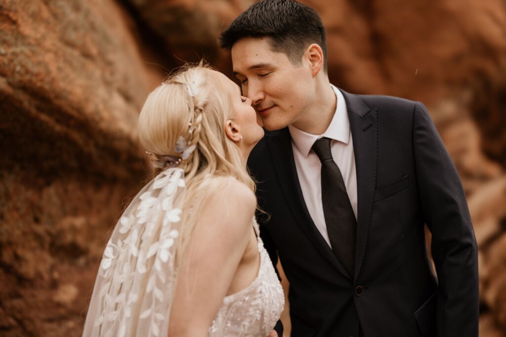 couple gazes at each other on red rocks at colorado springs' garden of the gods during wedding photo session.