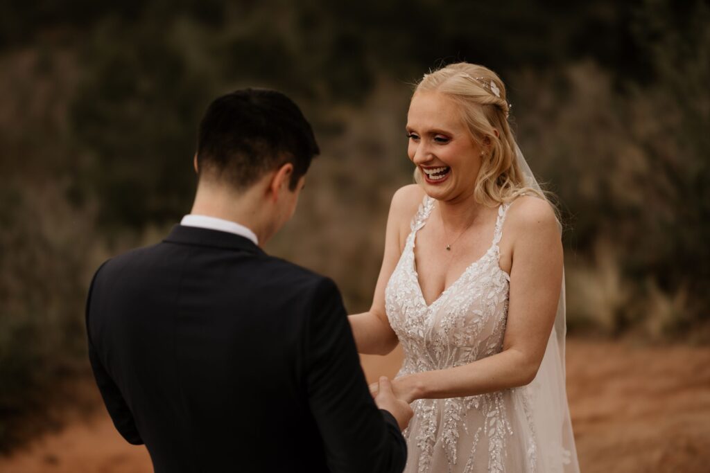 couple stands on red rocks and holds hands at colorado springs' garden of the gods during wedding portrait session.