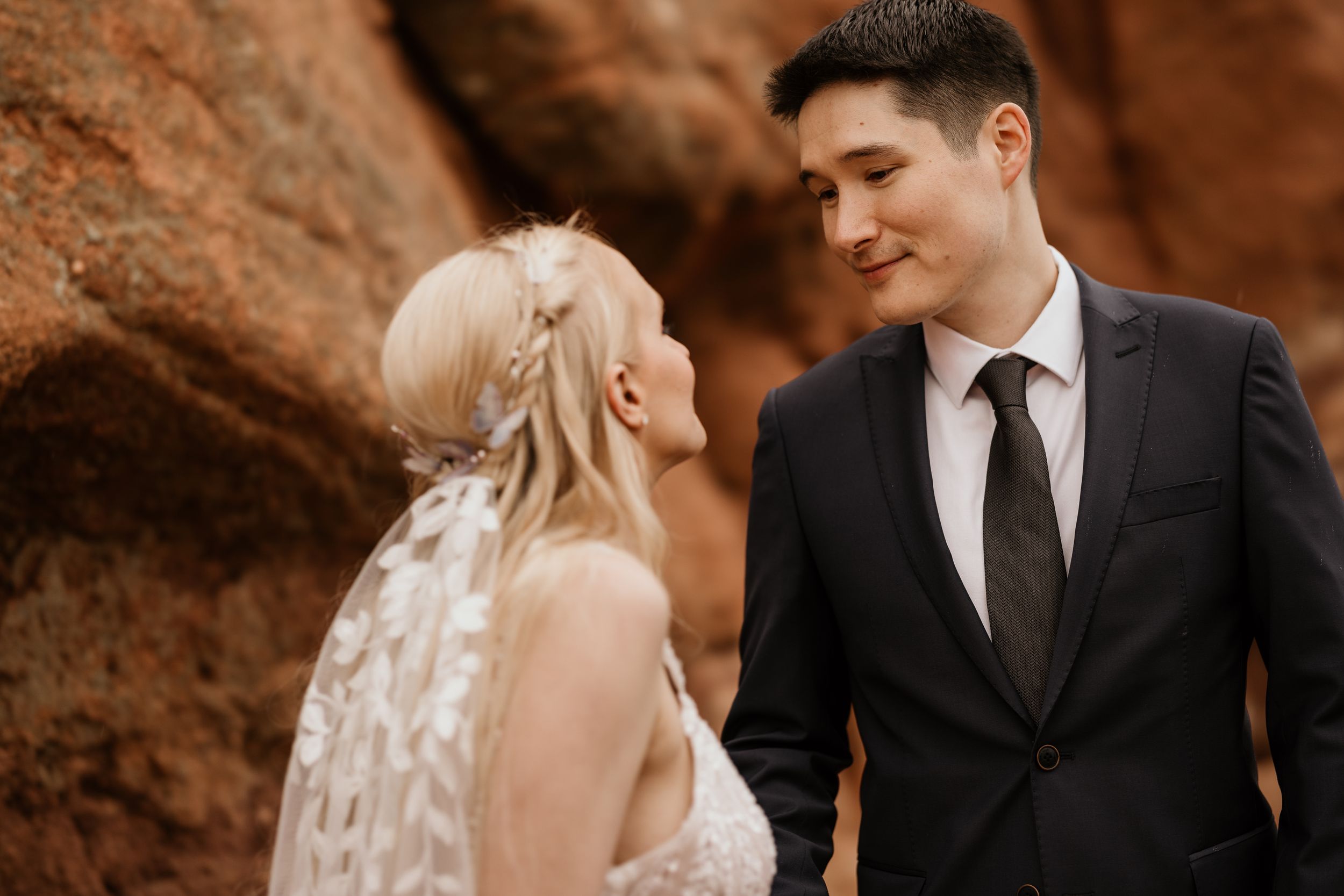 couple gazes at each other on red rocks at colorado springs' garden of the gods during wedding photo session.