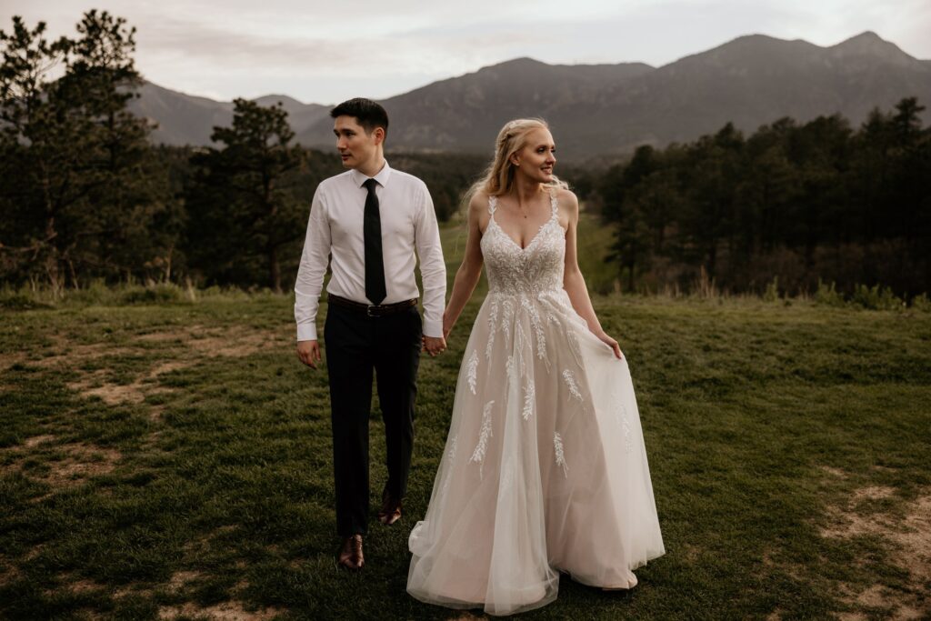 bride holds onto grooms arms and leans her head on his shoulder during wedding portraits in colorado springs.