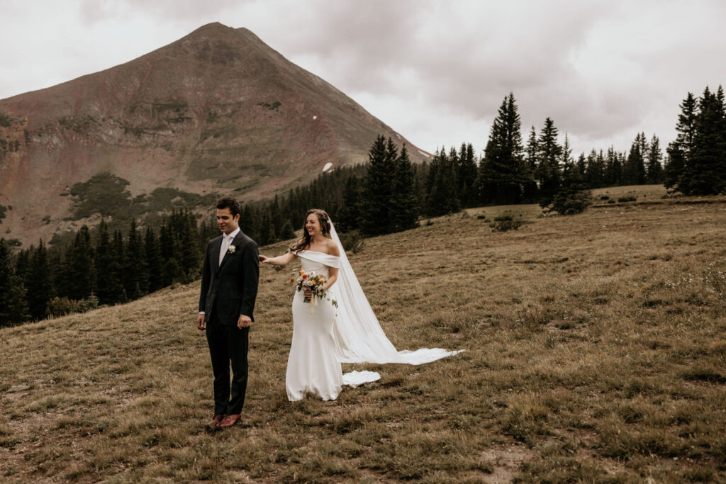 Bride taps groom on shoulder during first look at their colorado mountain micro wedding.