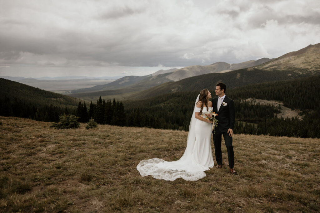 Bride and groom stand in front of mountain vistas during fall micro wedding in colorado.
