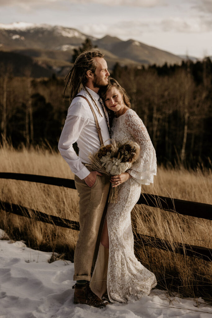 Bride and groom lean on each other with the colorado mountains in the background during their adventure elopement.