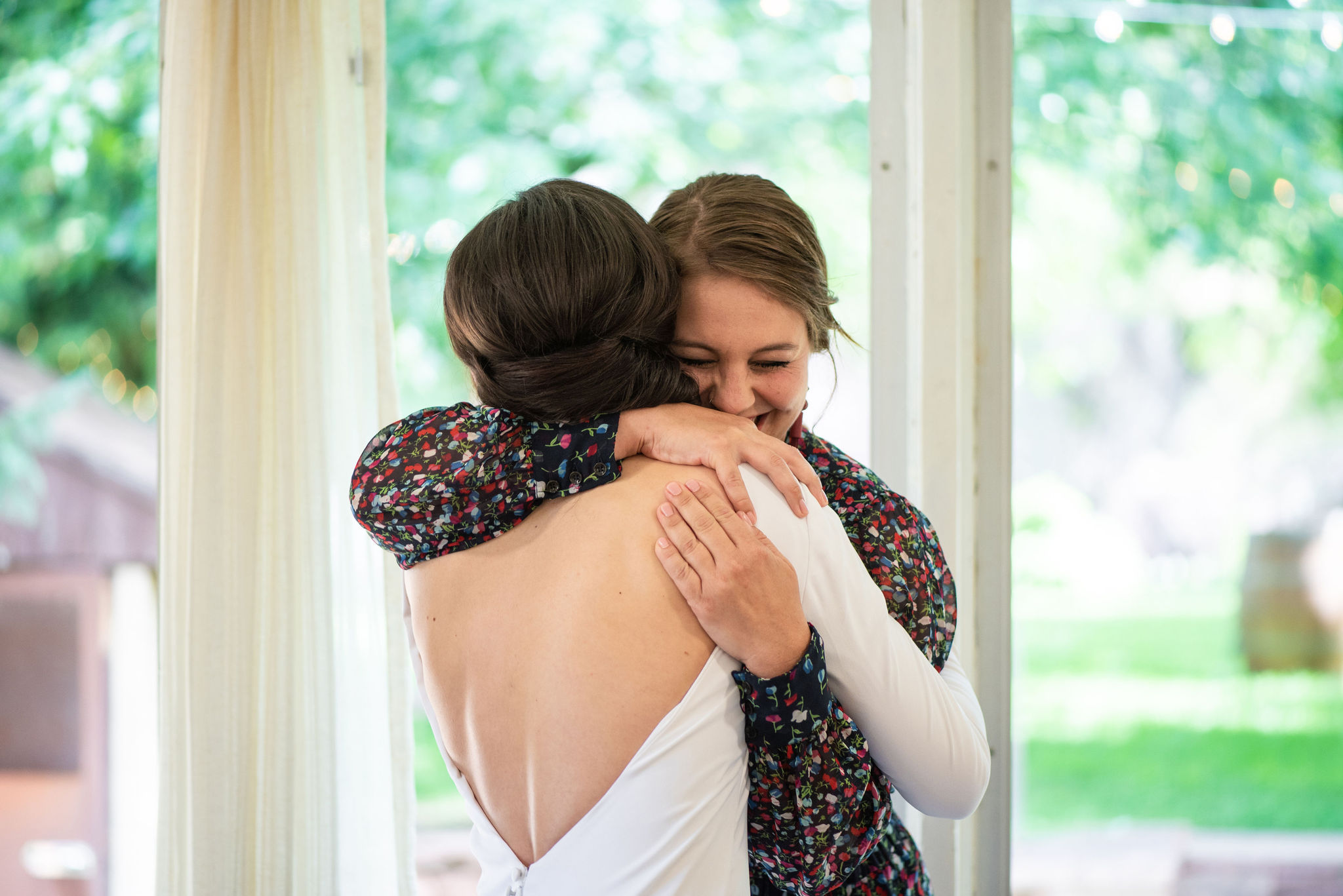 bride hugs friend in getting ready area at river bend wedding venue for her colorado micro wedding.