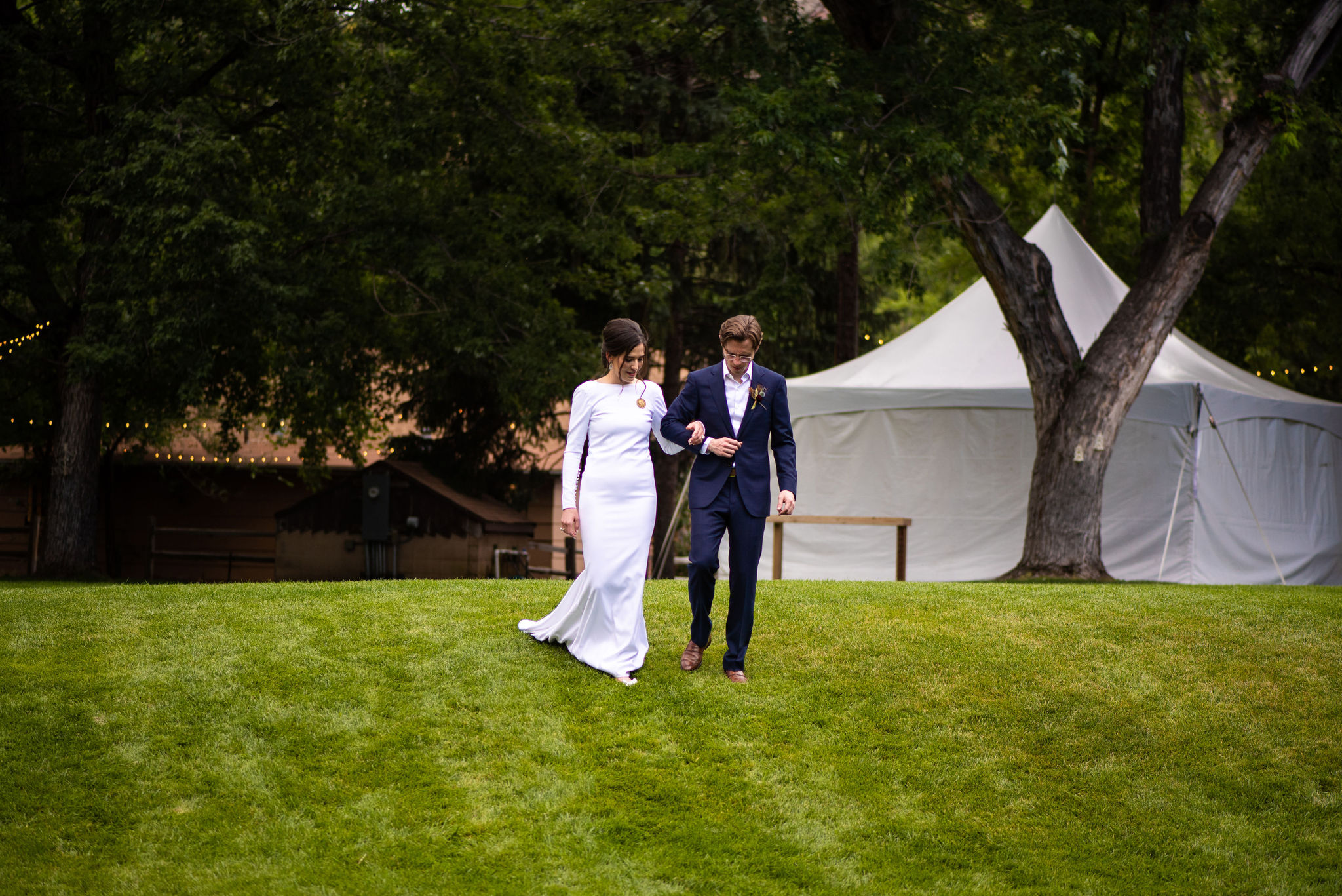 bride and groom walk down lawn at river bend wedding venue in lyons colorado.