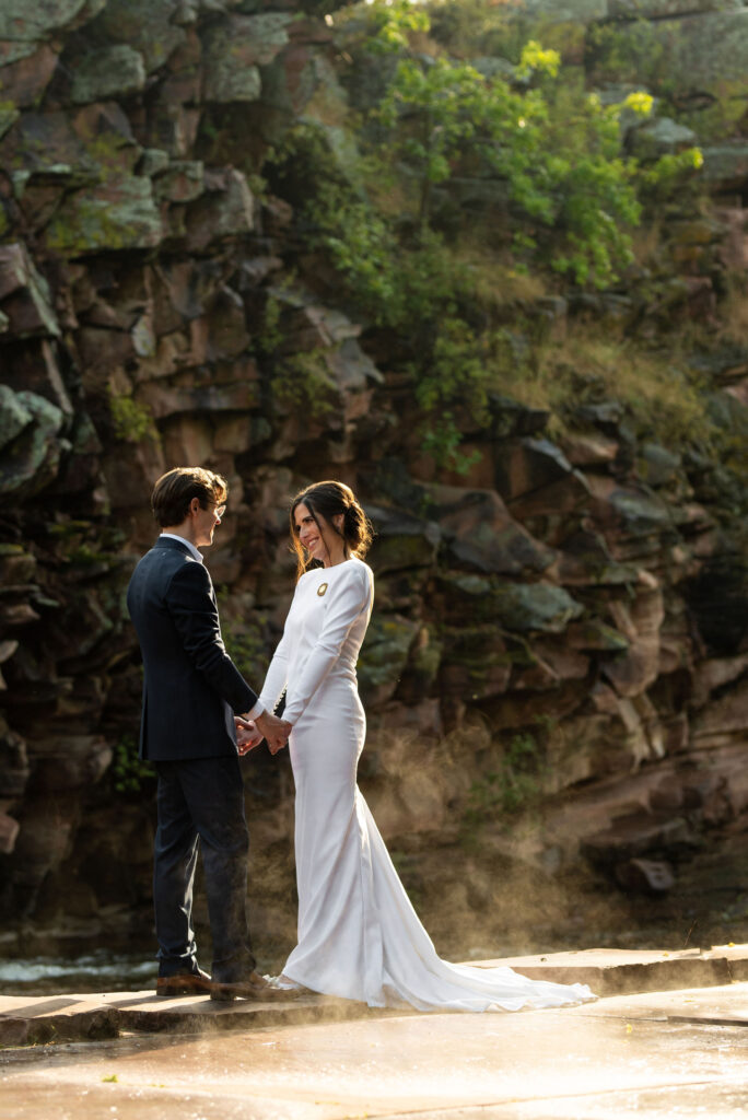 bride and groom stand by rock edge at river bend venue for their colorado micro wedidng.