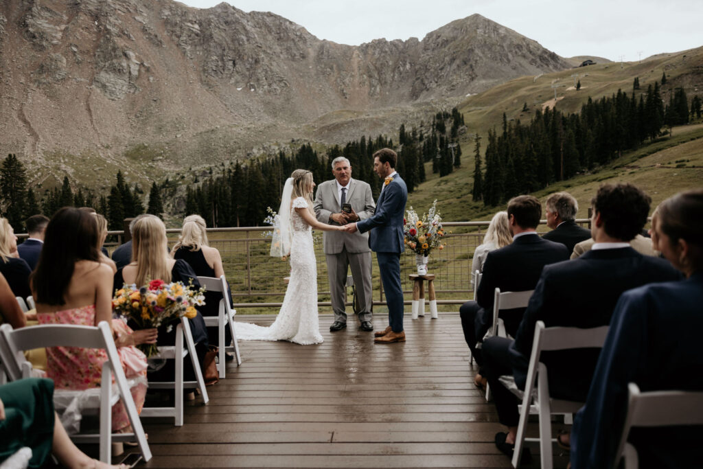 bride and groom stand at ski mountain wedding ceremony in colorado.