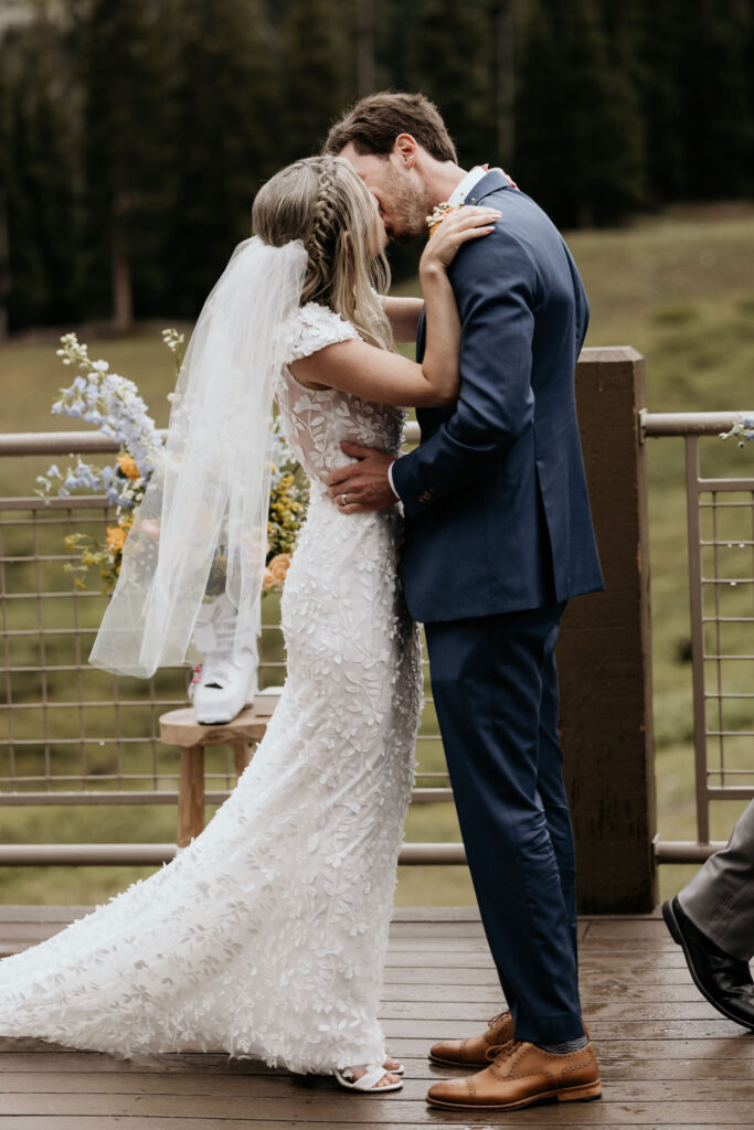 bride and groom kiss during ski mountain wedding ceremony at black mountain lodge in colorado.
